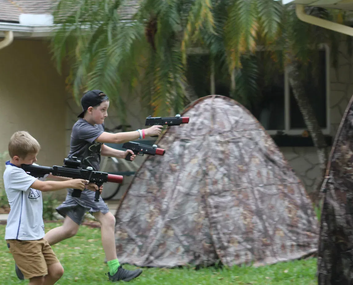 Boys playing mobile laser tag in a backyard